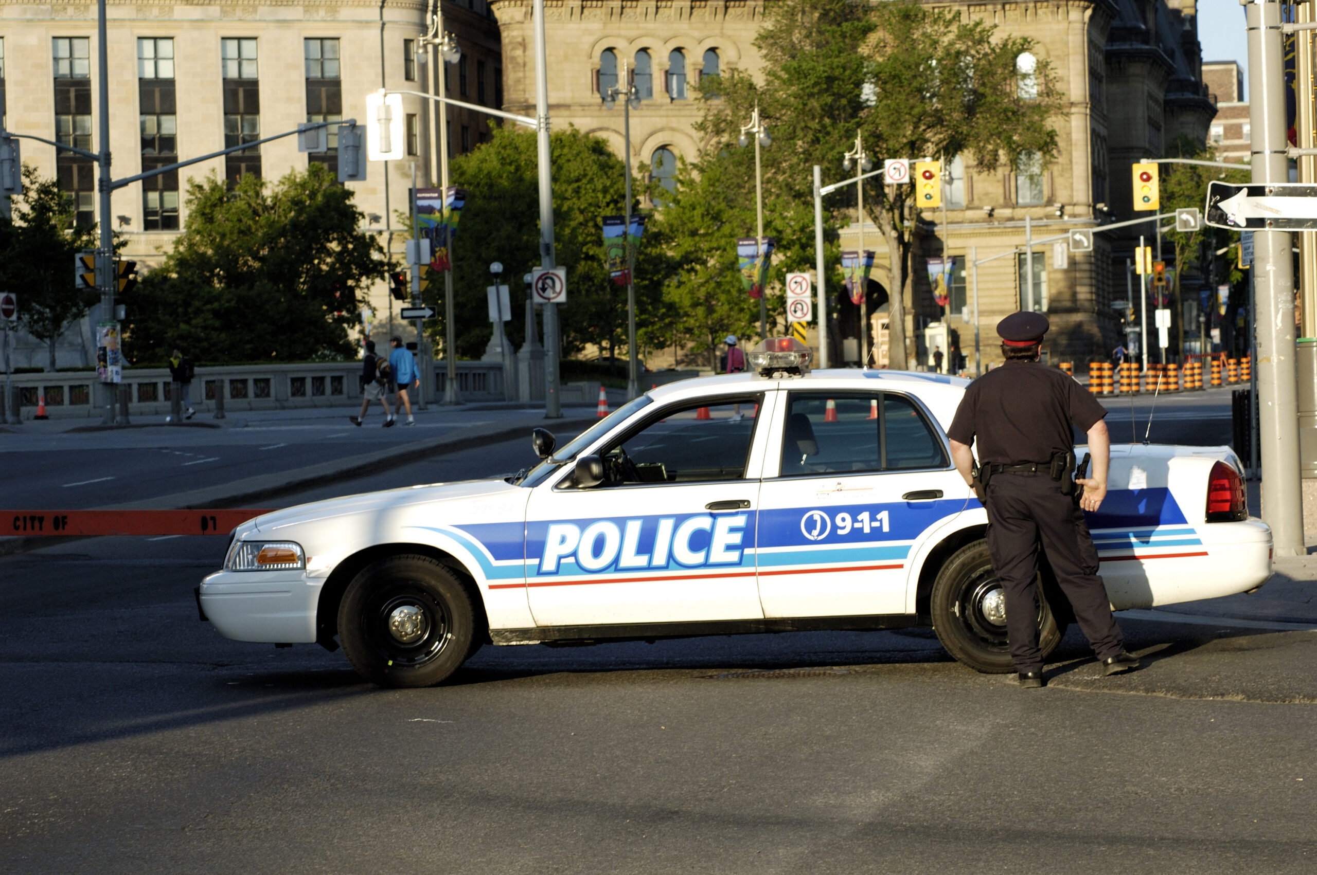 "Stock Photo of policman besidepolice vehicle,blocking a road."